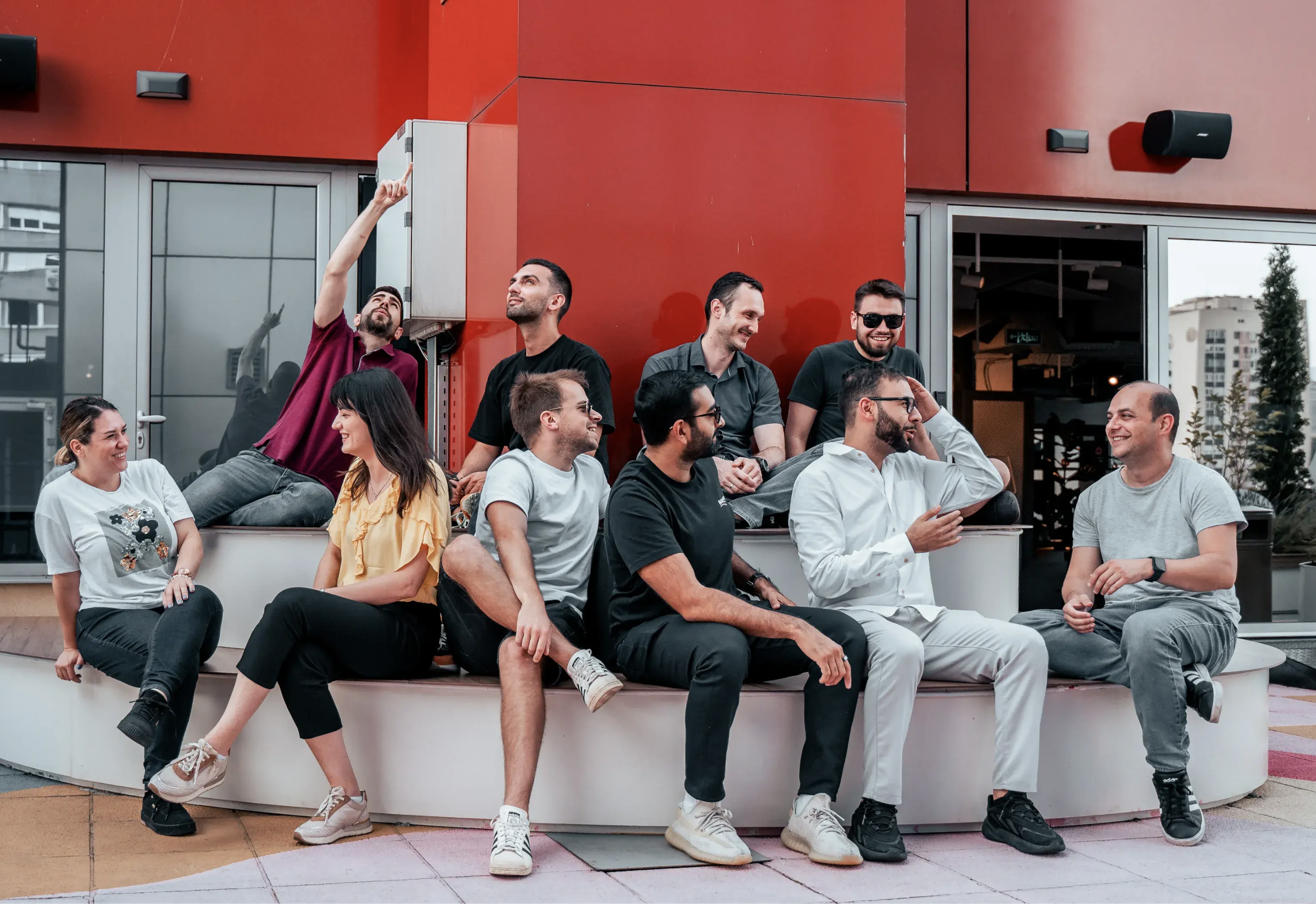 Ministry of Programming development team sitting together on white seating area with red wall